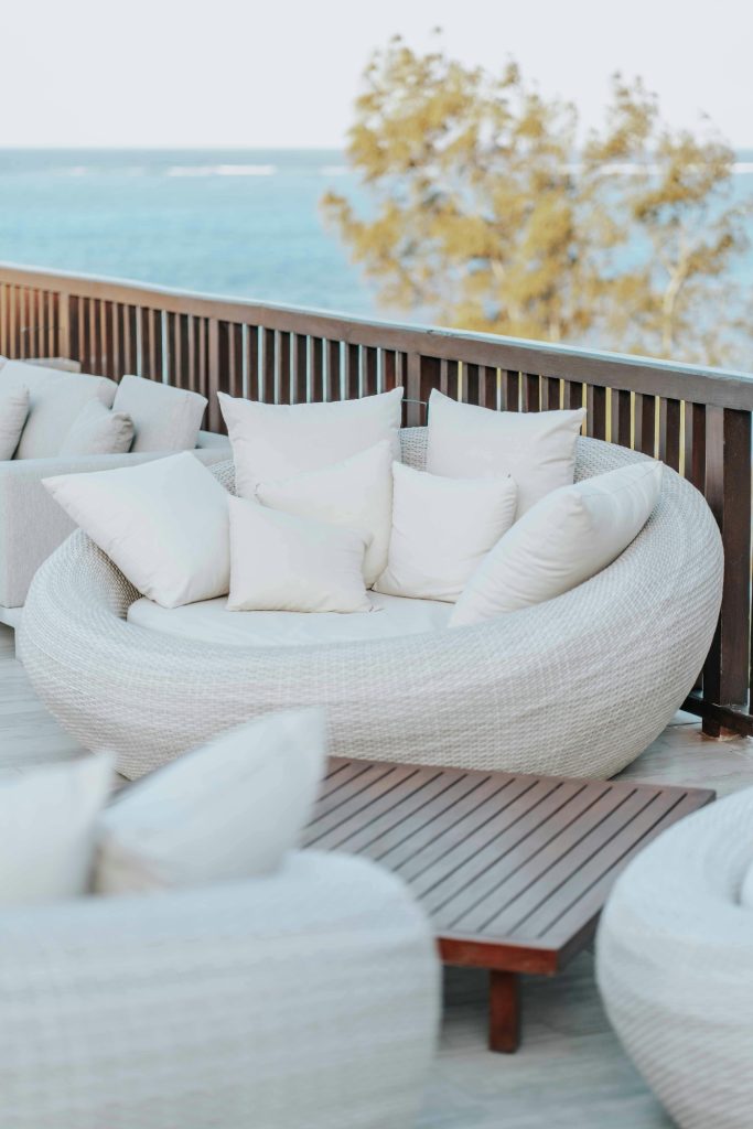 Cozy outdoor seating area with a round white sofa and scattered pillows.