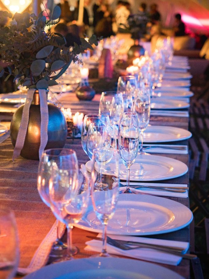 Elegant dining table set with plates, glassware, and decorative centerpieces.