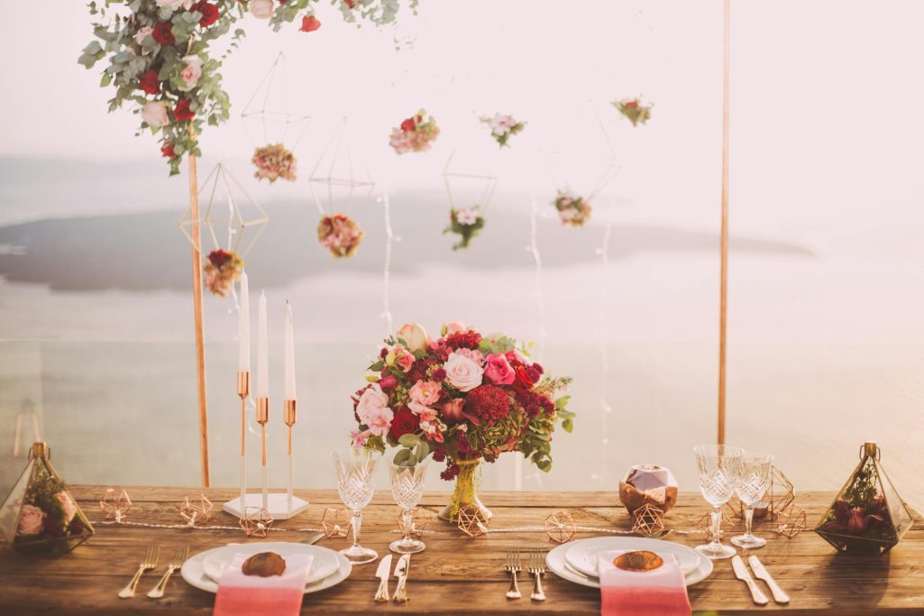 A beautifully arranged table setting with flowers and elegant glassware against a scenic backdrop.