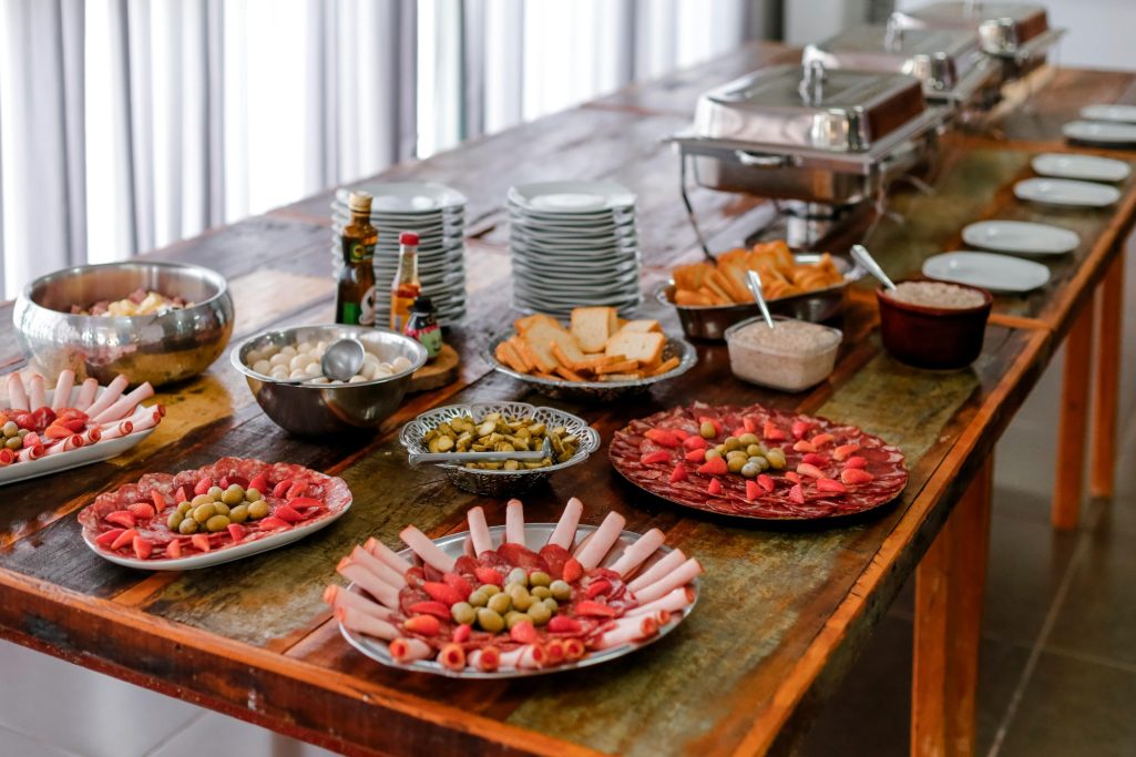 A buffet table with various platters of meats, cheeses, olives, and bread.