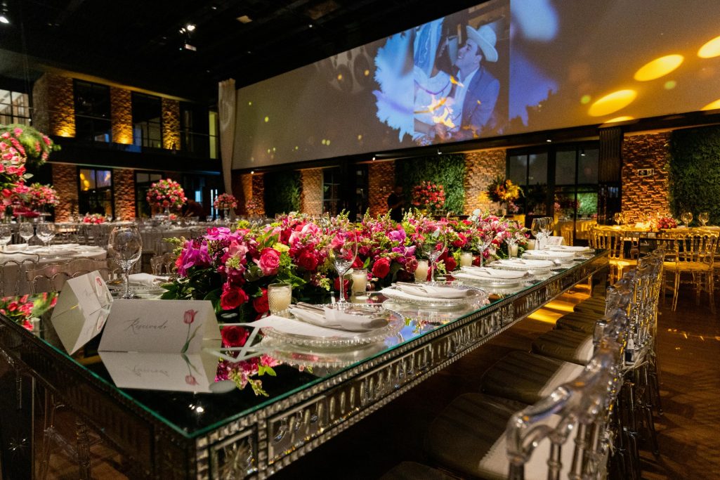 Elegant banquet setup with floral centerpieces and a large screen in an upscale venue.