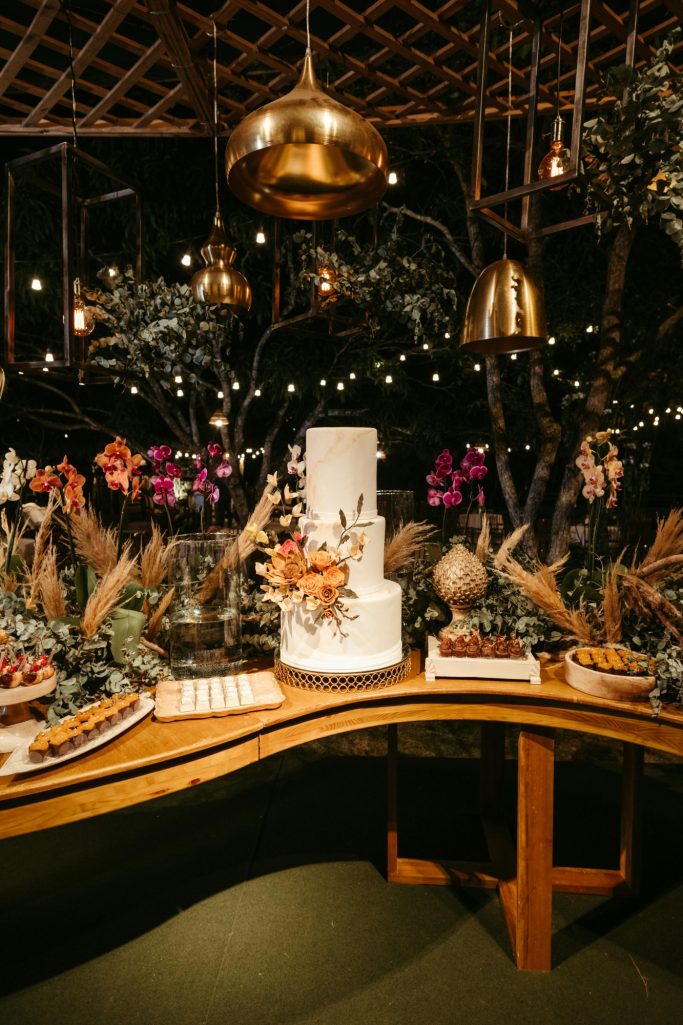 Elegant cake displayed on a table, surrounded by floral arrangements and decorative elements.